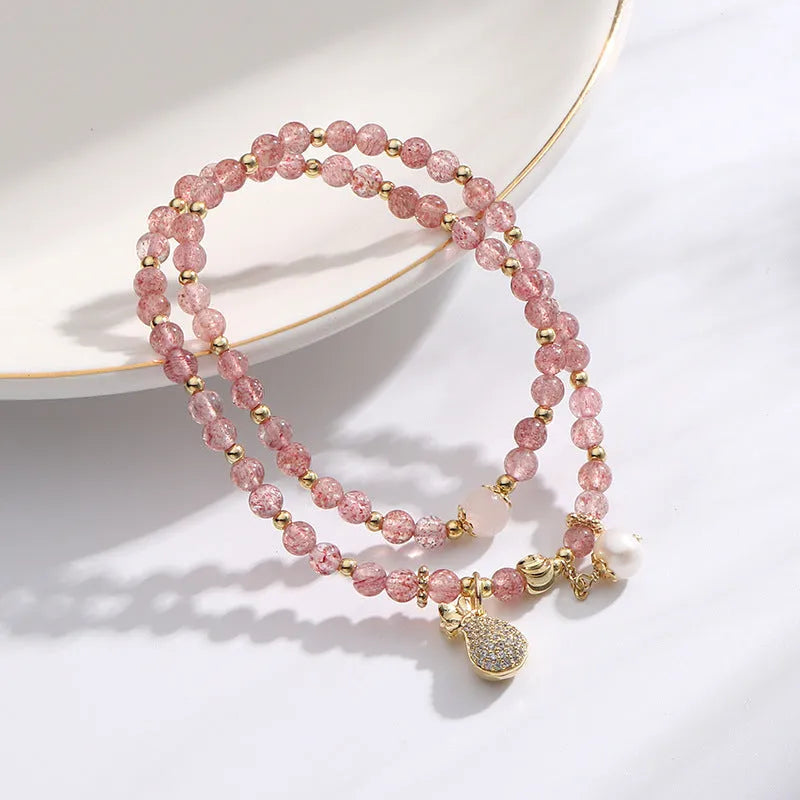 Women's geometric strawberry quartz crystal bracelet with a silver wallet money charm.