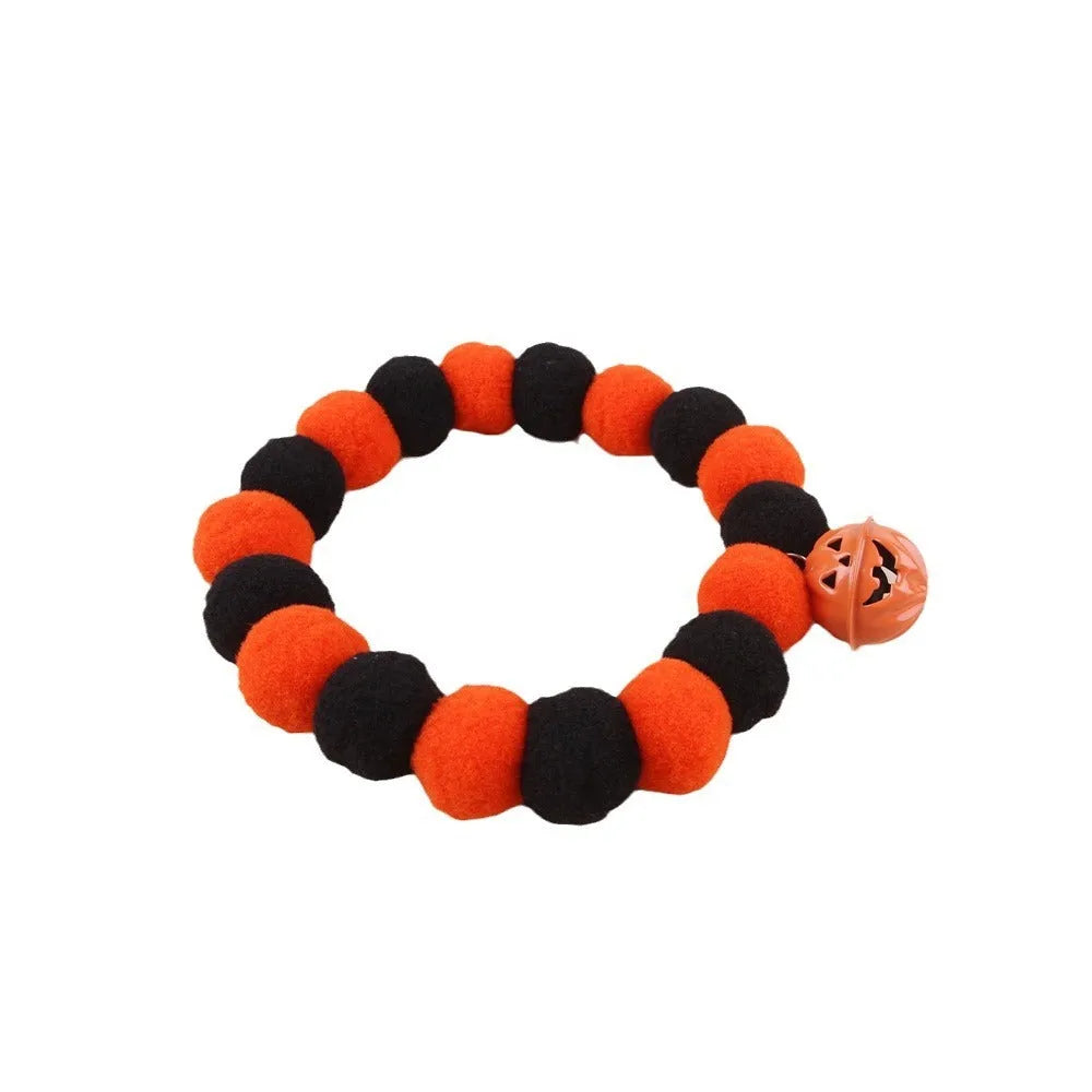 Orange pumpkin-shaped cat collar with a naughty cat face print, laid flat.