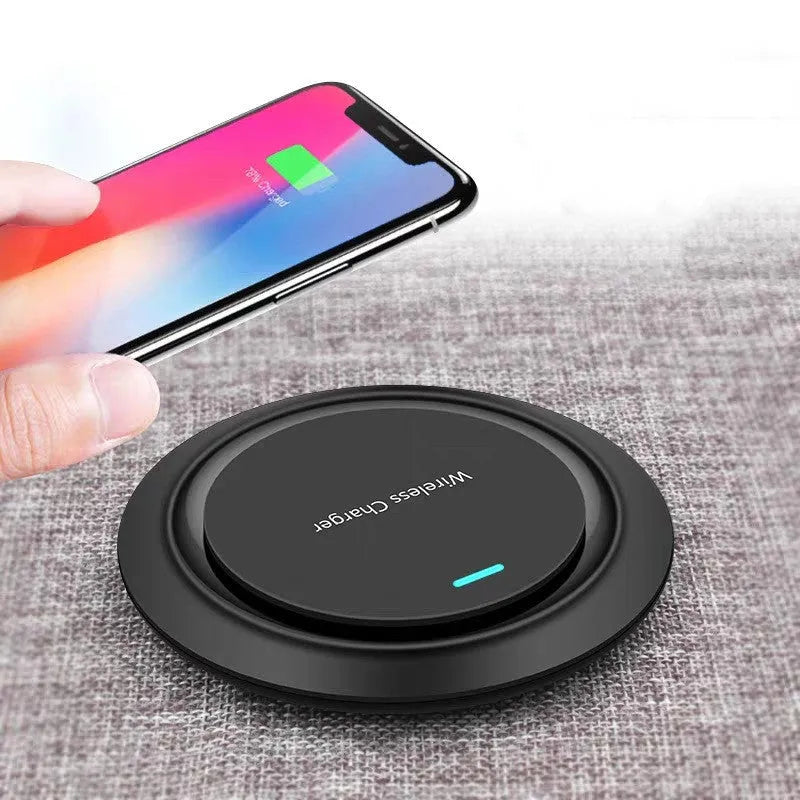 Round white wireless charging pad on desk next to mobile phone