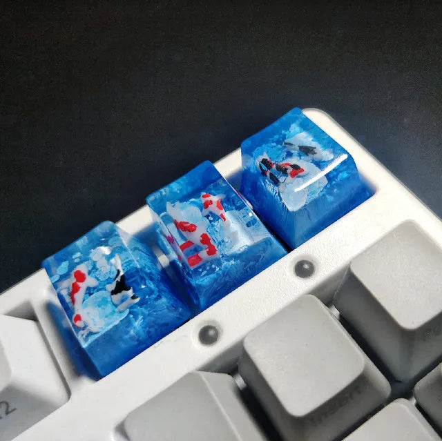 Close-up of a custom resin keycap featuring a detailed blue and orange koi fish scene, designed for Cherry MX mechanical keyboards.