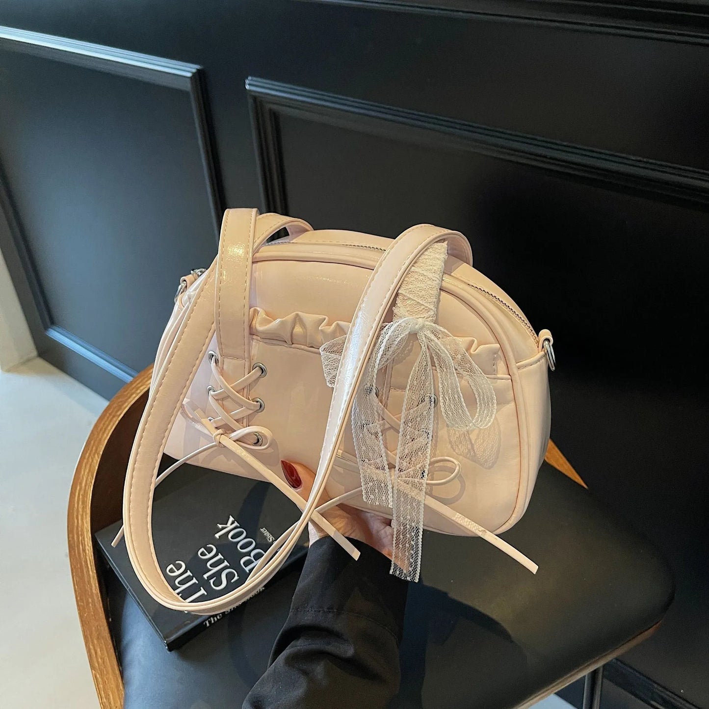 Milky white women's shoulder handbag with a large bandage bow and visible stitching, showing the internal phone pocket.