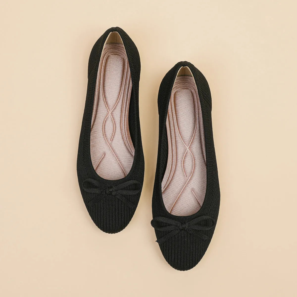 Women's black fabric flat pumps with a bow detail on the round toe, shown on a white background.