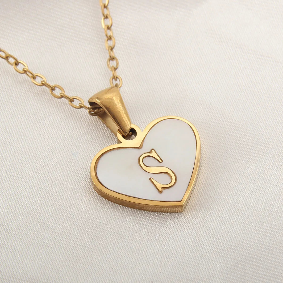 Gold-plated clavicle necklace with a white shell heart pendant, personalised with a letter from A to Z.