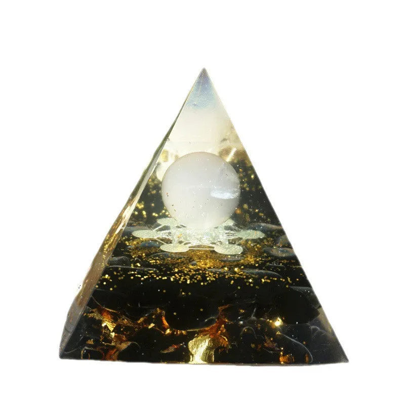 A small 6cm clear epoxy resin pyramid ornament containing pieces of natural crystal gravel on a flat surface.