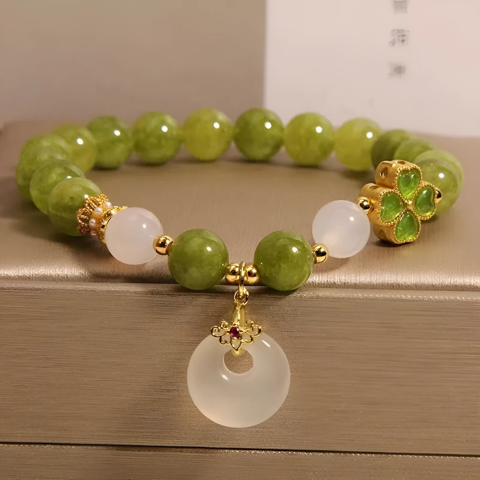 Green tourmaline women's bracelet with four-leaf clover safety buckle and geometric drop shape.