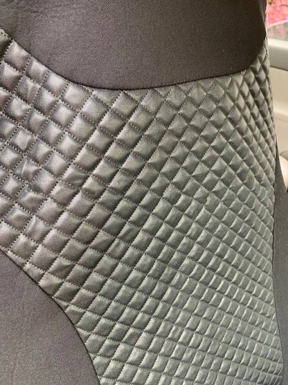 Black quilted universal car seat cover fitted on a front car seat, showing diamond stitching and plastic hook fastenings.