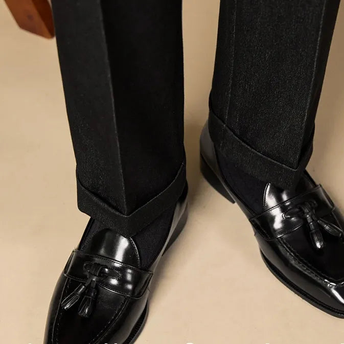 Men's black genuine leather tassel loafers with a rubber sole, shown from a side angle.