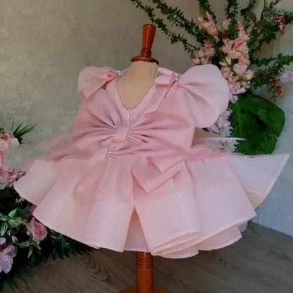 Pink flower girl dress with puffy sleeves and princess bow, shown on mannequin