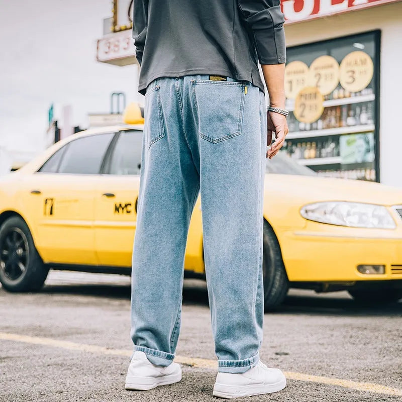 Men's dark blue loose straight fit cotton jeans with a zipper fly, shown on a hanger.