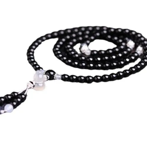 A bracelet made of 108 black geometric agate beads on a wrist.
