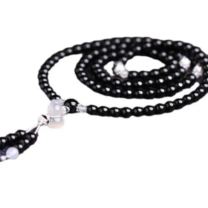 A bracelet made of 108 black geometric agate beads on a wrist.