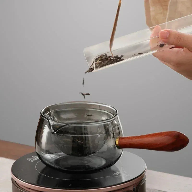 Glass teapot with wooden handle showing transparent borosilicate construction and removable infuser