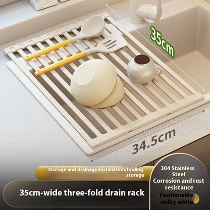 A milky white foldable stainless steel kitchen draining rack collapsed flat beside a kitchen sink.