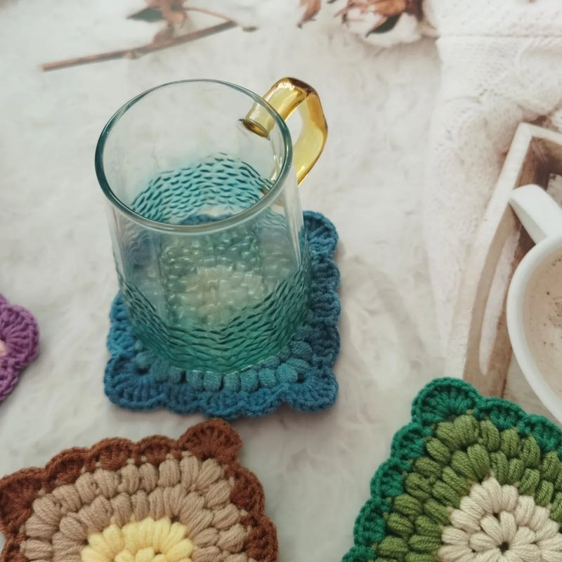 Crocheted cup coaster placemat with grandmother lattice pattern design made from wool yarn available in Emerald, Sea Salt Blue, Dream Purple, and Fog Brown colour options for insulated mug and hot drink protection