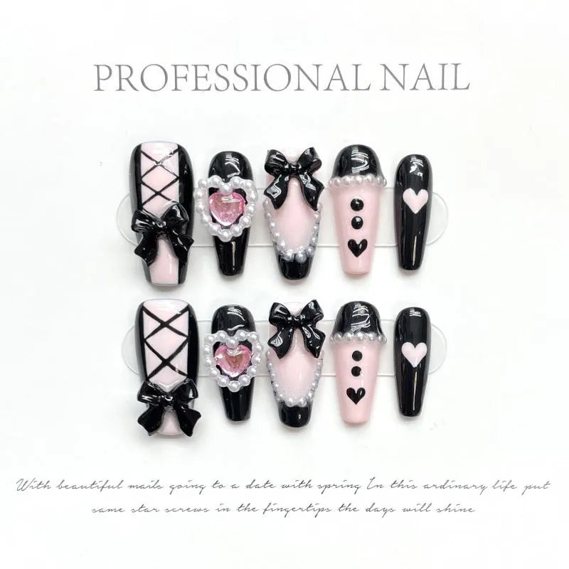 Hand-painted black and pink heart false nail set with detachable bow ornament, shown in sizes XS to L.