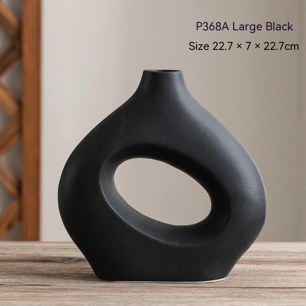 White ceramic circle vase with hand-painted coloured glaze on wooden table with dried flowers