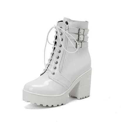Women's black chunky heel ankle boots with round toe and front lace-up design on a wooden floor.