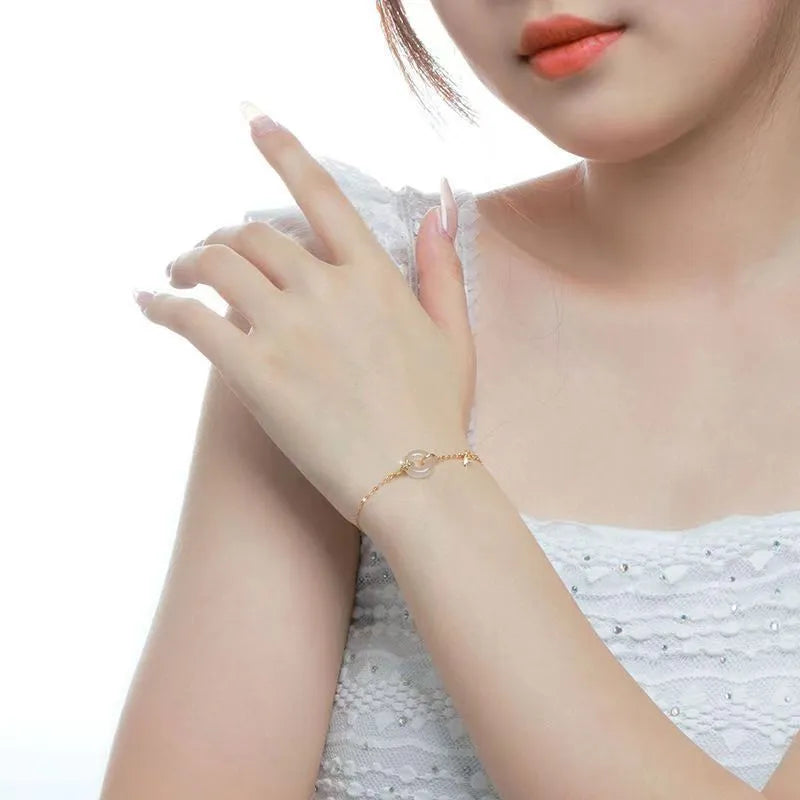 Gold-colour women's bracelet with peace symbol buckle and white chalcedony stone on silver band.