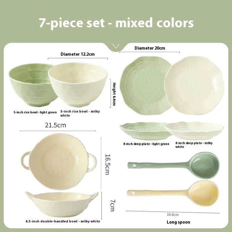 Boxed set of seven solid-colour ceramic plates and bowls on a table.
