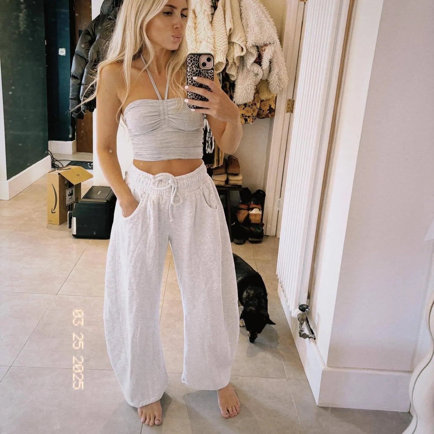 Loose grey cropped sweatpants with drawstring waist and side pockets on a casual model.