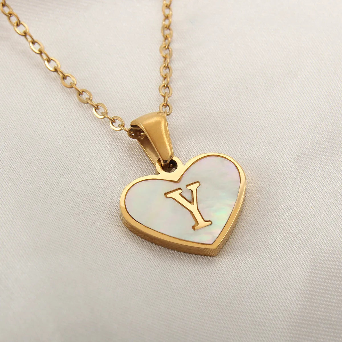 Gold-plated clavicle necklace with a white shell heart pendant, personalised with a letter from A to Z.