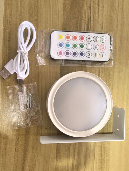 Black magnetic LED painting lamp with remote control on a white wall.
