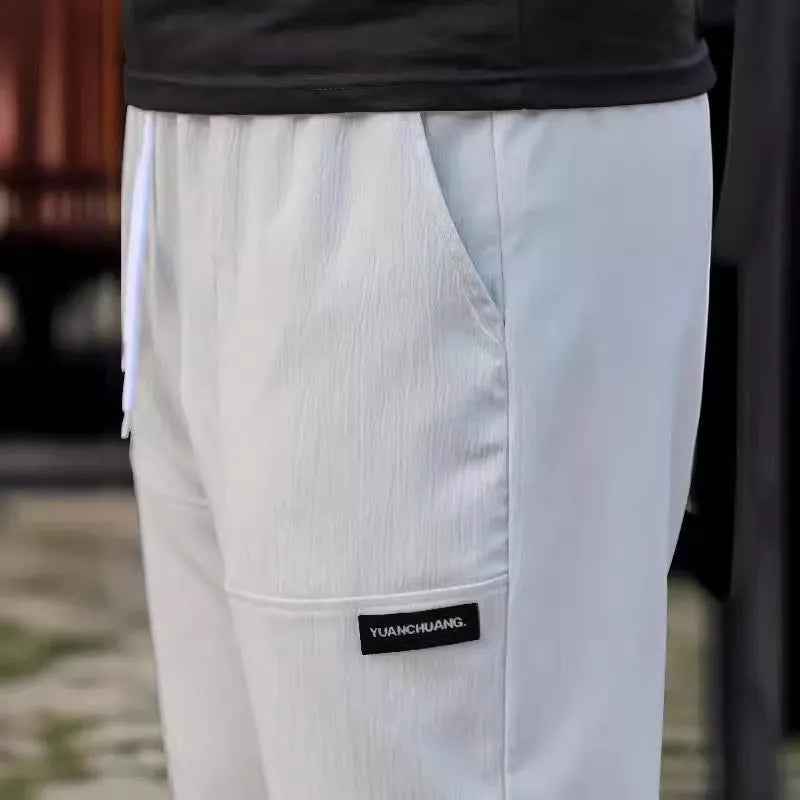 Men's polyester trousers for spring and autumn in light grey, shown in a casual setting
