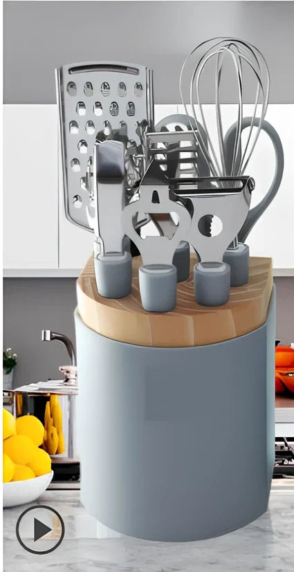 Stainless steel kitchen utensil set with whisk, grater, peeler, scissors and other tools on grey background