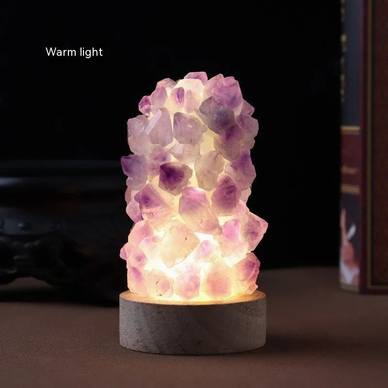 Miniature amethyst crystal tooth flower night light glowing with warm light on a wooden surface.