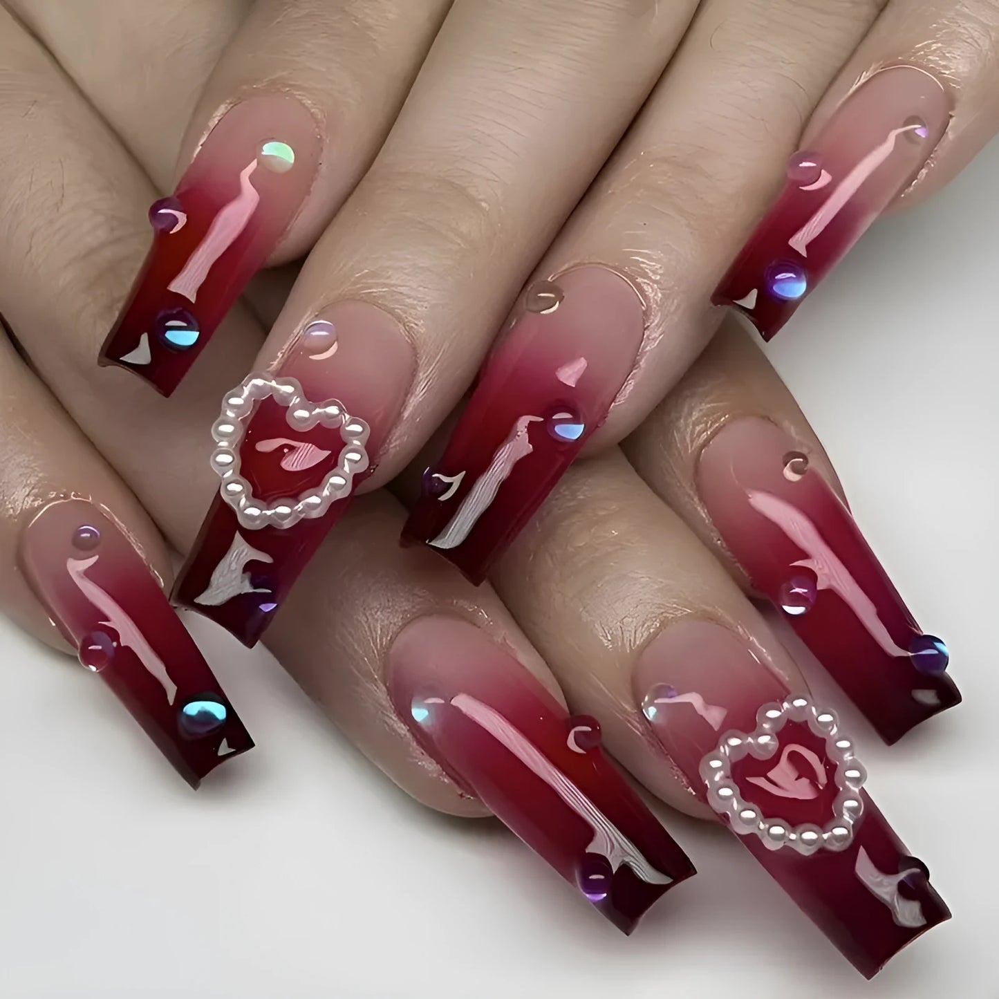 Set of long ballet-style fake nail tips with wine red gradient, white plaid pattern, and pearl heart decorations
