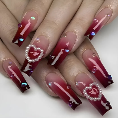 Set of long ballet-style fake nail tips with wine red gradient, white plaid pattern, and pearl heart decorations