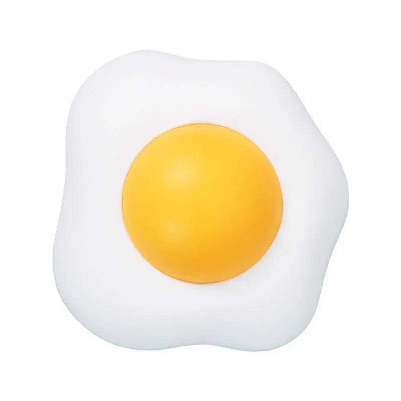 Interactive plush catnip ball toy shaped like a fried egg, stuck to a wall with a cat batting at it.