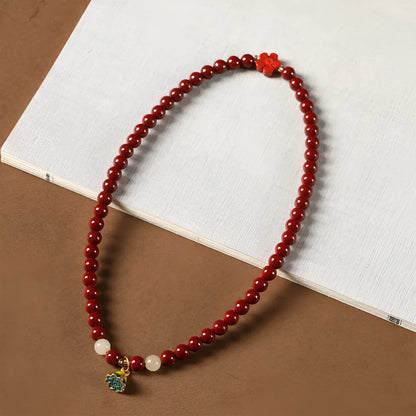 Close-up of a hand-woven purple gold cinnabar bead bracelet with a lotus seedpod charm.