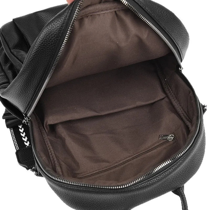 Genuine leather multi-functional commuting backpack with flap pocket, polyester lining, and metal letter patchwork details in black.