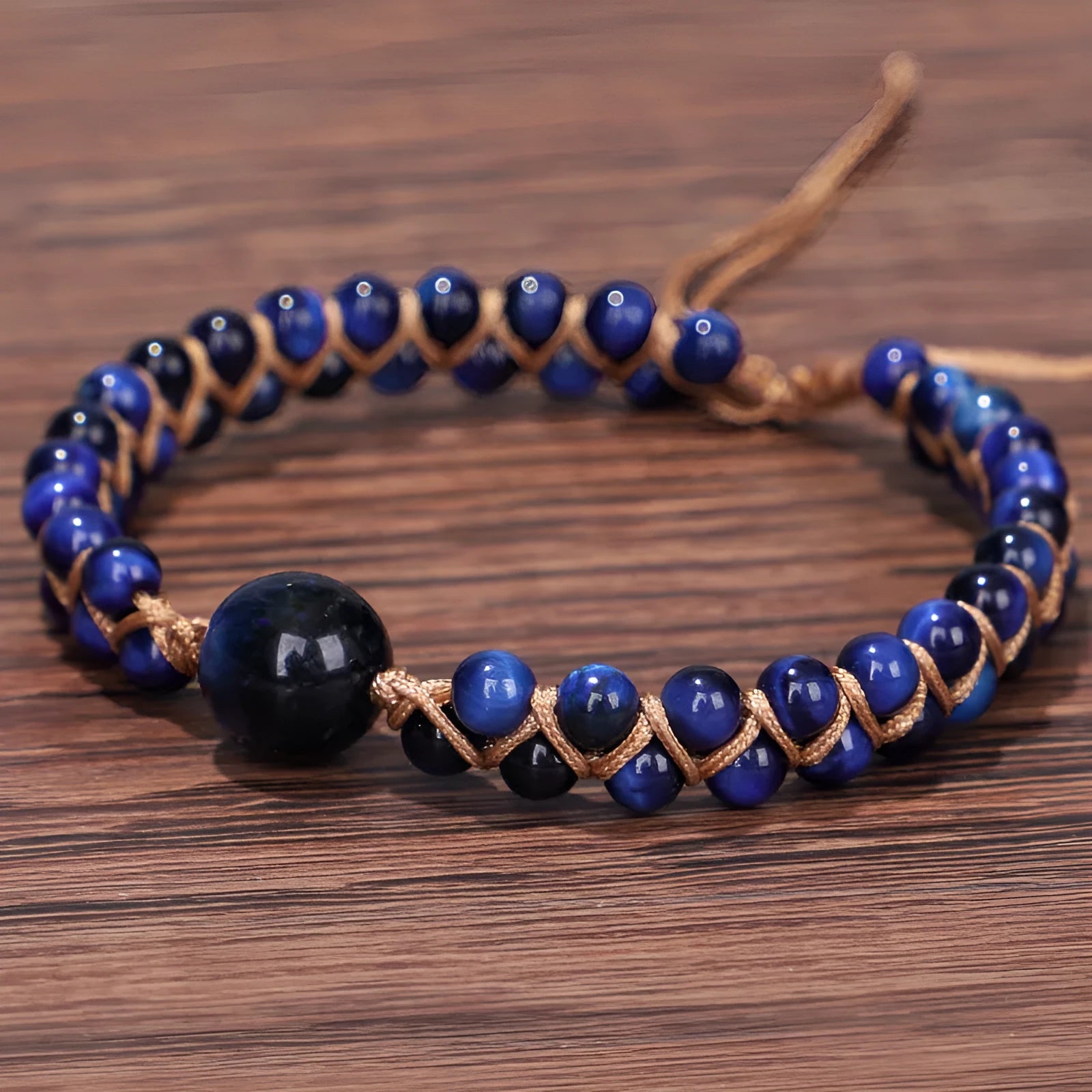 Handmade geometric pull bracelet woven from blue tigereye stone beads on a wrist.