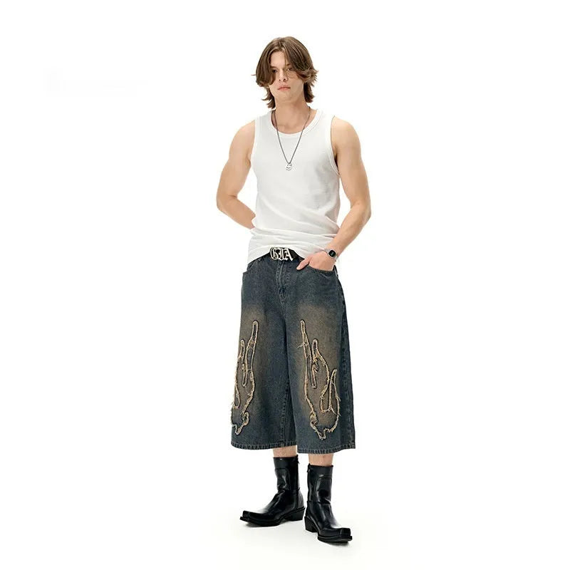 Men's black denim shorts with a cropped flame embroidery patch on the leg.