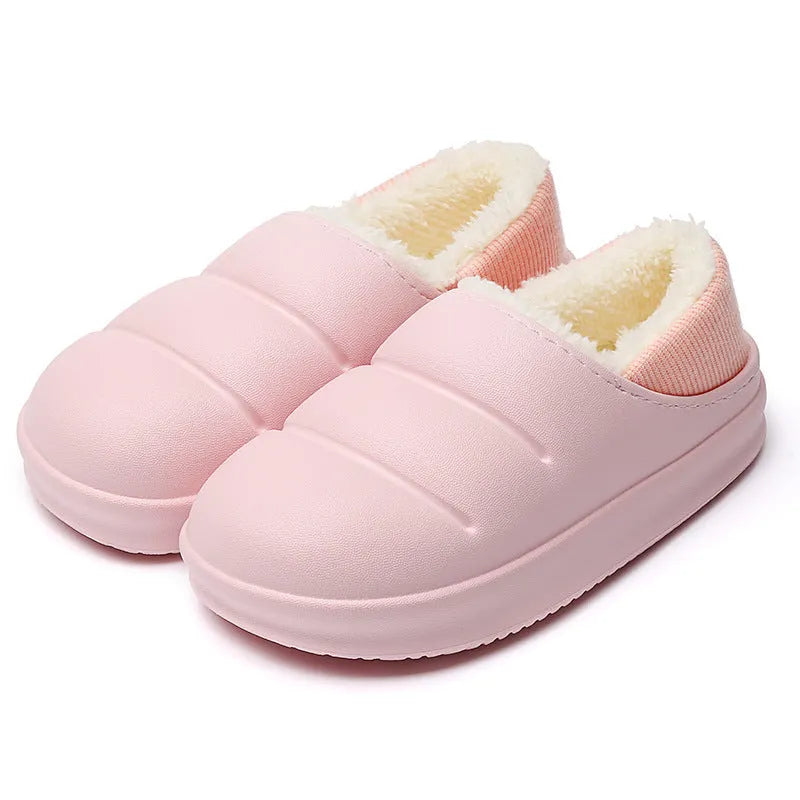 A pair of yellow EVA sleeve-style slippers with a plush lining and a textured non-slip sole, on a wooden floor.