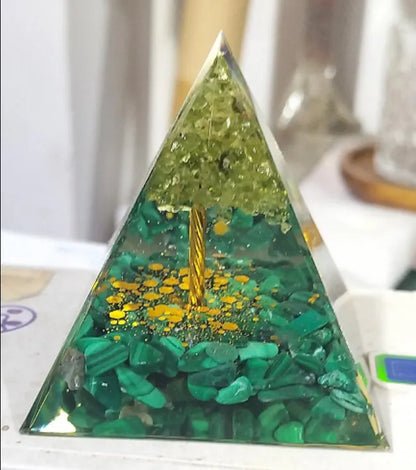 A small 6cm clear epoxy resin pyramid ornament containing pieces of natural crystal gravel on a flat surface.