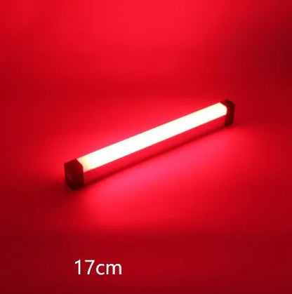 Blue rechargeable LED light tube with USB plug and push-button switch on a dark surface