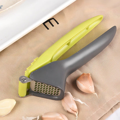 White plastic garlic masher with stainless steel crushing grid and ergonomic handle for kitchen use