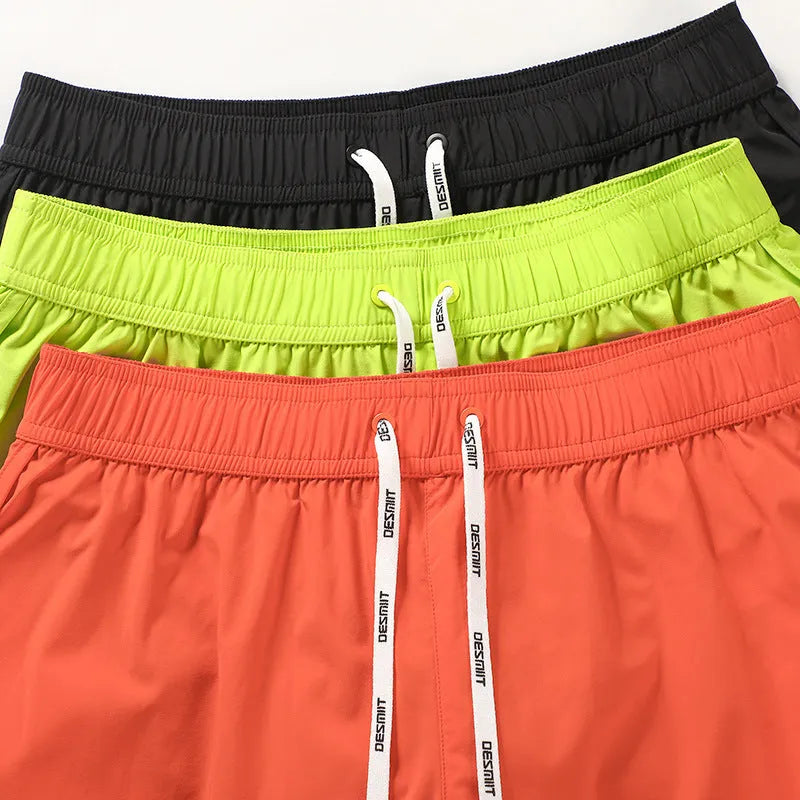 Men's loose orange beach shorts with elastic waist on a sandy shore