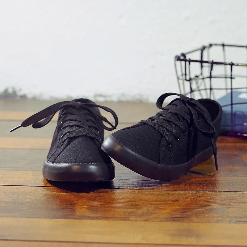 All-black women's canvas work shoes with flat rubber soles and lace-up front