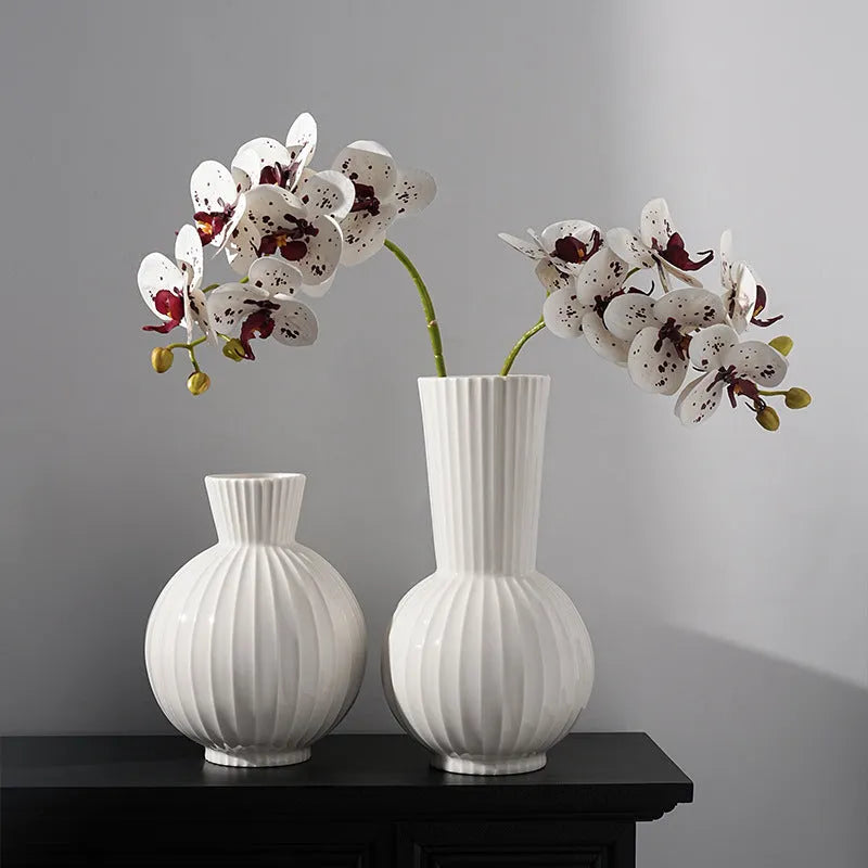 White ceramic ball-shaped vase with striped pattern, shown in small and large sizes with orchid arrangements