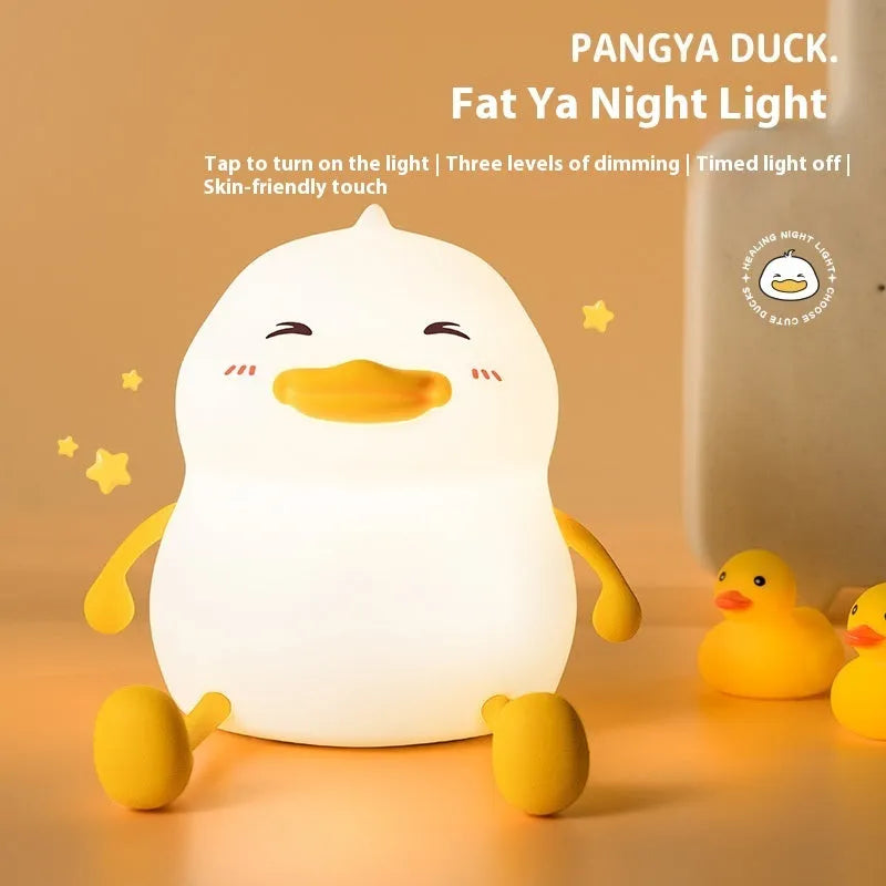 Chubby Night Light with soft glow on bedside table, holding a mobile phone in its silicone cradle.