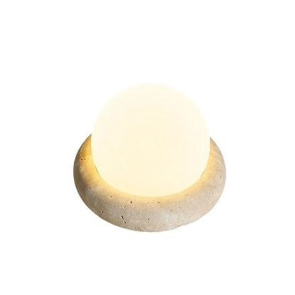Modern white bedside night lamp with remote control on a wooden table.