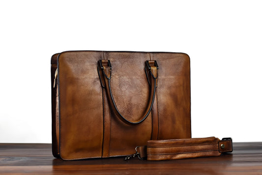 Men's khaki leather horizontal business handbag with front zipper, shown on a table.