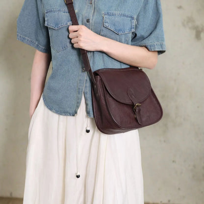 Genuine leather messenger bag in brown colour showing flap closure and textured cowhide material