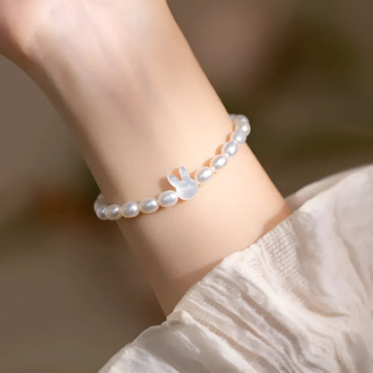 White pearl and shell bead elastic bracelet with silver rabbit charm on wrist