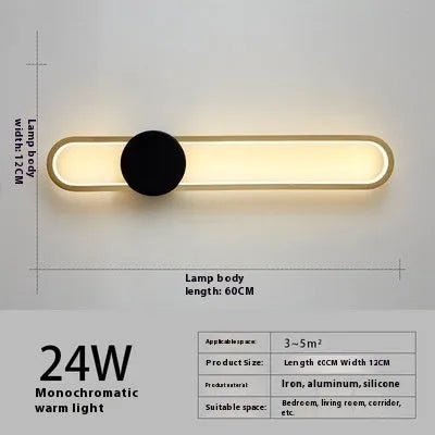 Round black iron wall sconce with integrated LED light glowing on a modern grey wall