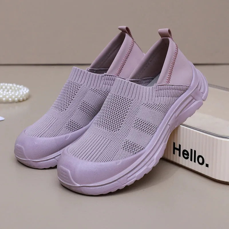 Women's one pedal slip-on shoe in black with cloth upper and PVC sole, showing round toe and flat heel design.